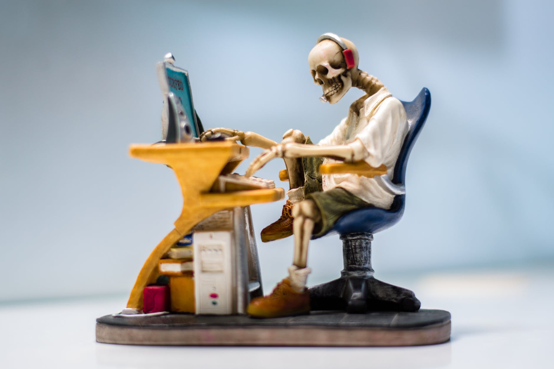 figurine of human skeleton sitting infront of computer